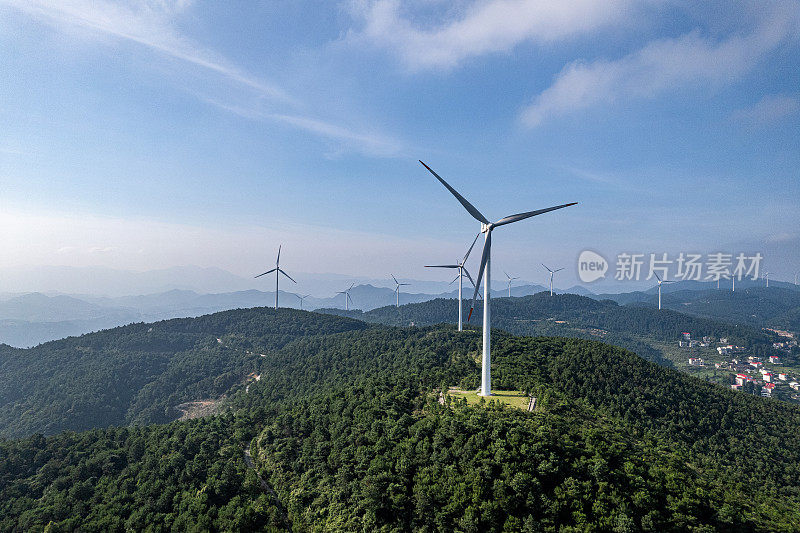 在晴朗的天气里，森林覆盖的山顶上的一组风力涡轮机
