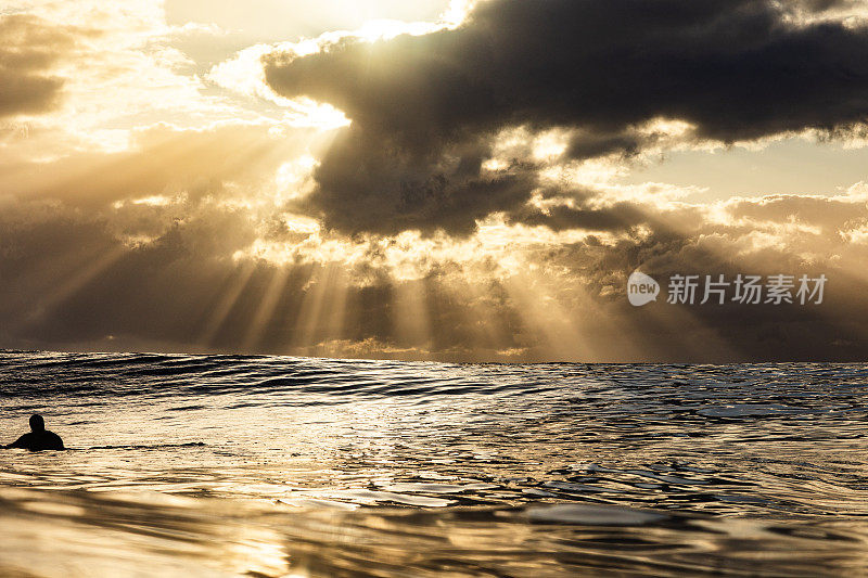 日出与戏剧性的光线反射在海洋表面在金色的光
