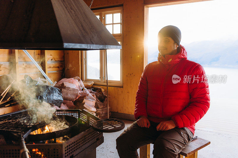 挪威峡湾，一名男子在炉火旁取暖