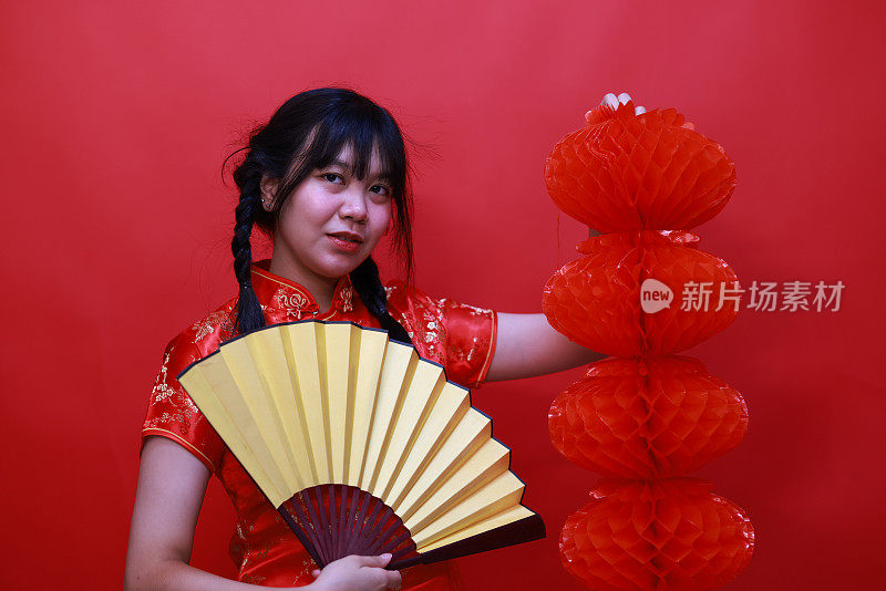 一个打着红灯笼和黄扇子的欢呼的女孩在摄影棚的中国新年节日概念