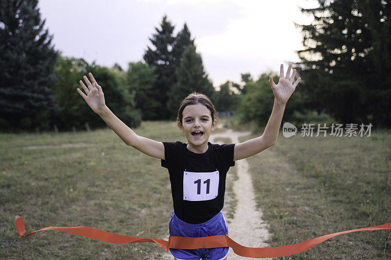 可爱的女孩赛跑选手越过终点线在大自然的比赛。
