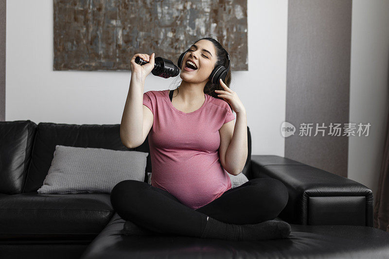 孕妇在家享受快乐时光，听音乐，唱歌和跳舞