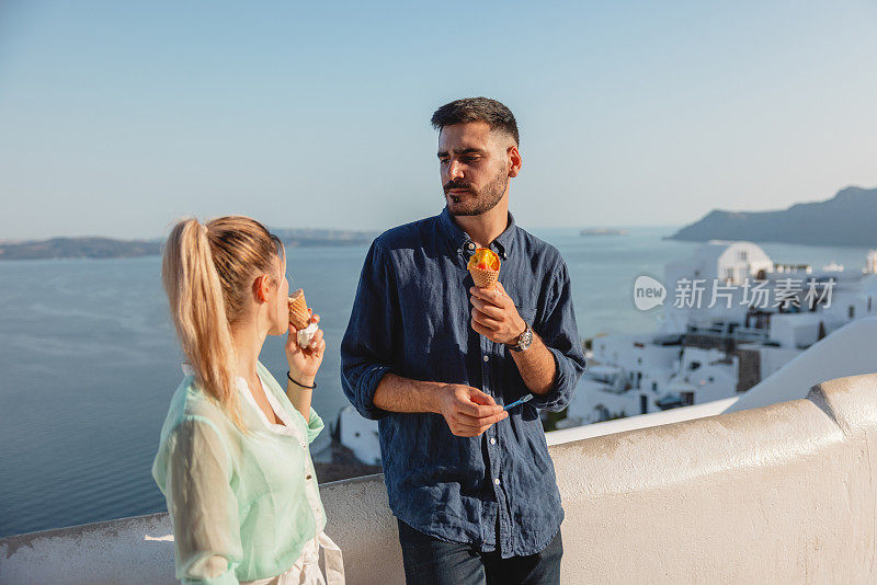 一对年轻的白人夫妇在圣托里尼岛享受约会，吃着冰淇淋