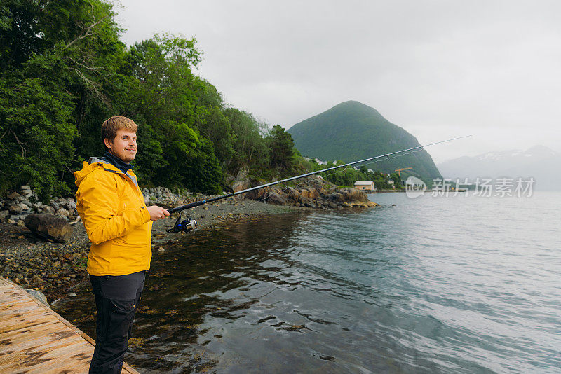 在挪威风景优美的峡湾钓鱼的黄色男子