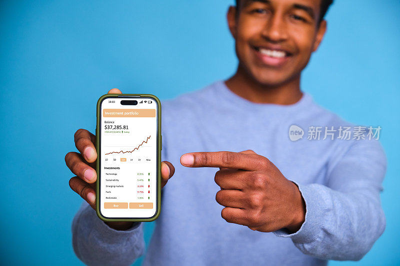 一个黑人拿着一部手机，指着一张股市图表。