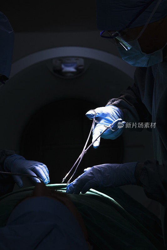 外科医生手持手术器械，病人躺在手术台上