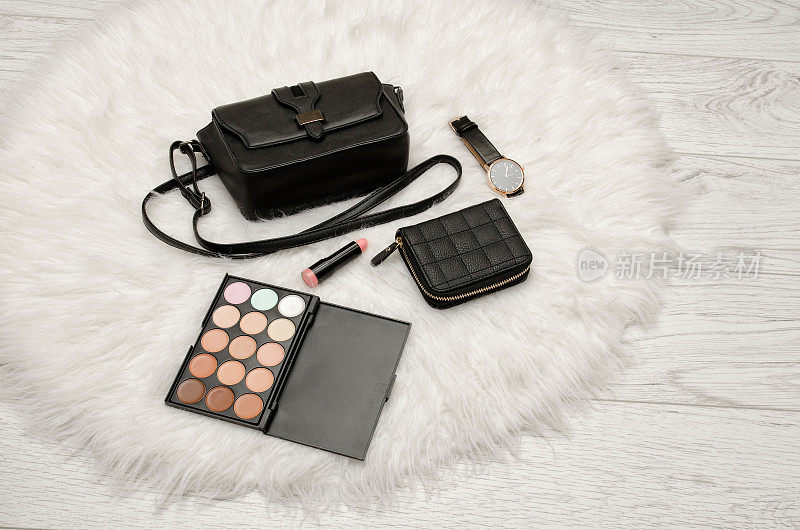 眼影，钱包，口红，手表和黑色手袋上的白色皮草。时尚的概念
