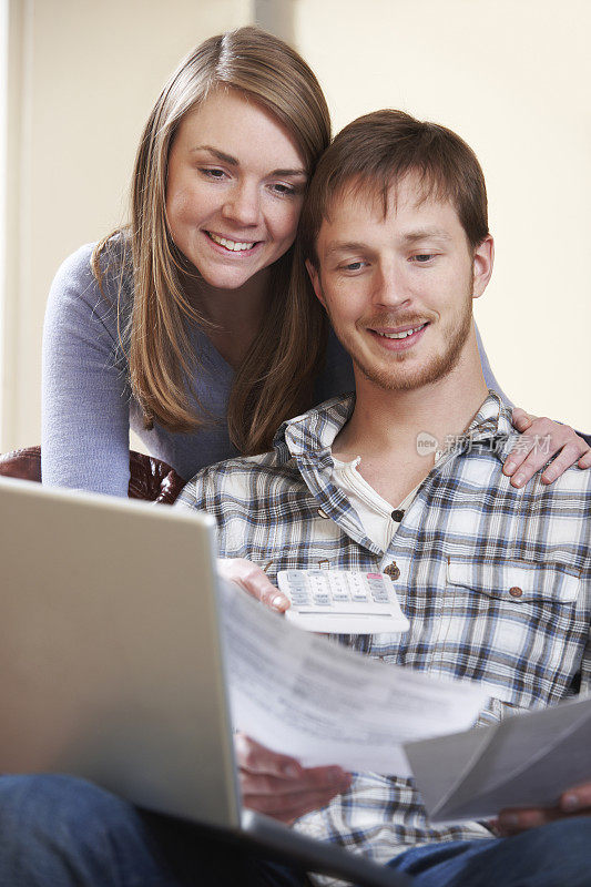 幸福的年轻夫妇在笔记本电脑上查看财务状况