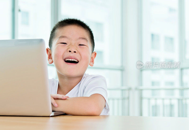 可爱的年轻亚洲男孩在室内笔记本电脑