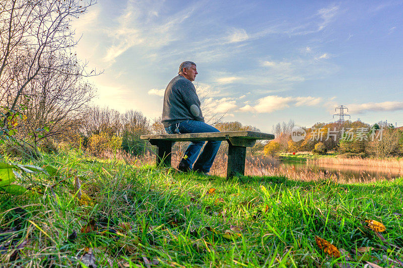 一位老人坐在乡间的长椅上