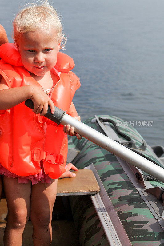 穿着救生衣的小女孩在充气船上划船