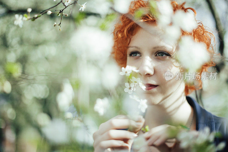 春天的肖像，恬静的红发女孩在盛开的树木