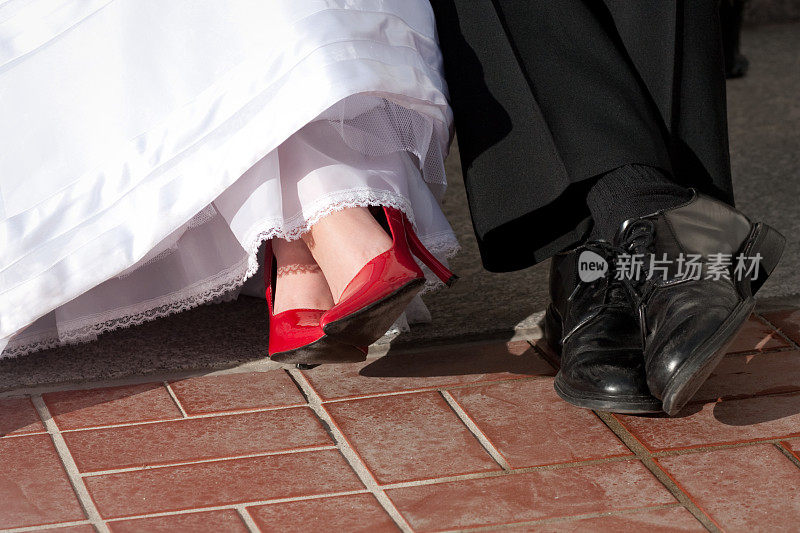 新娘和新郎脚与红色高跟鞋黑鞋