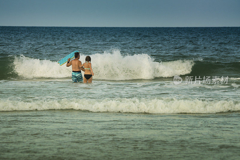 父亲和十几岁的女儿走近海浪