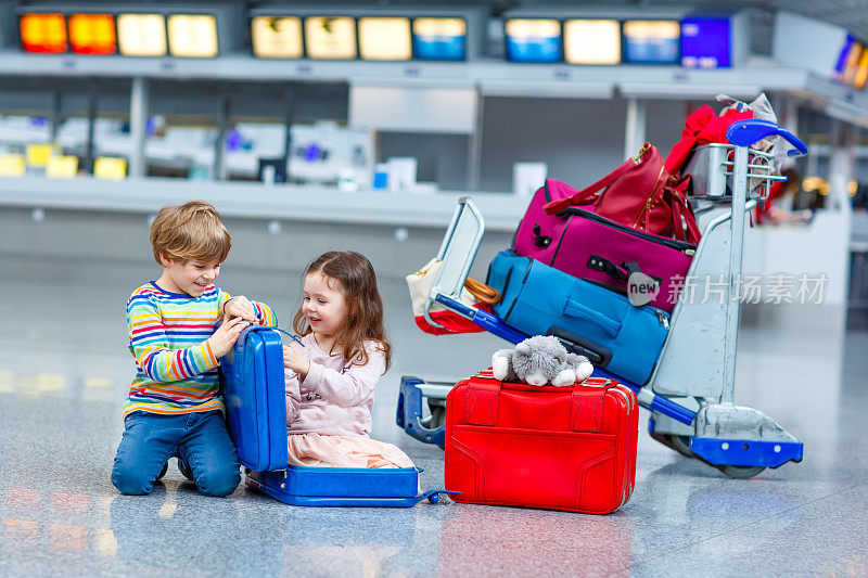 小女孩和小男孩坐在机场的行李箱上