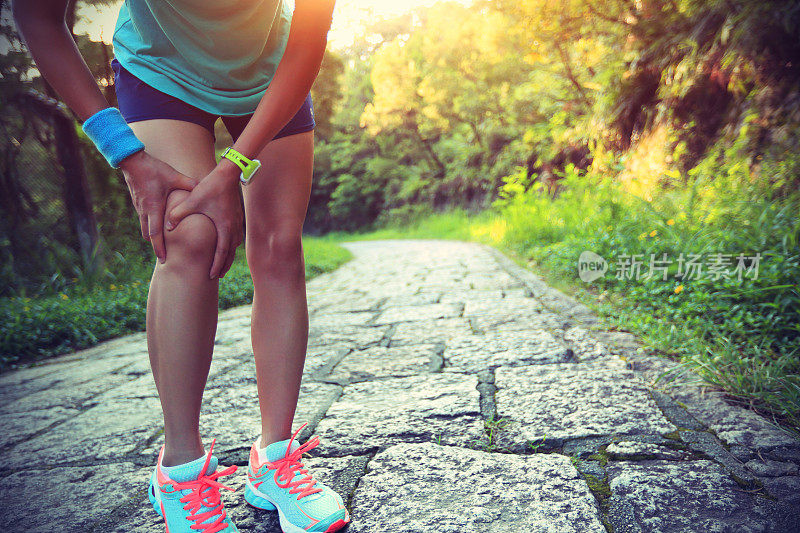 女跑步运动员扶着运动中受伤的膝盖