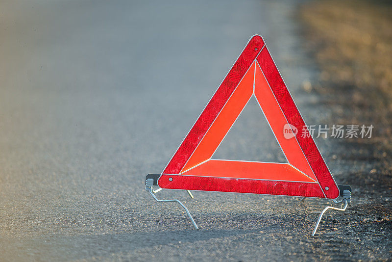 道路上的红色三角形警告标志表明一辆车抛锚了