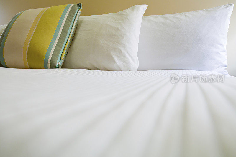 双人床上有条纹靠垫和两个枕头