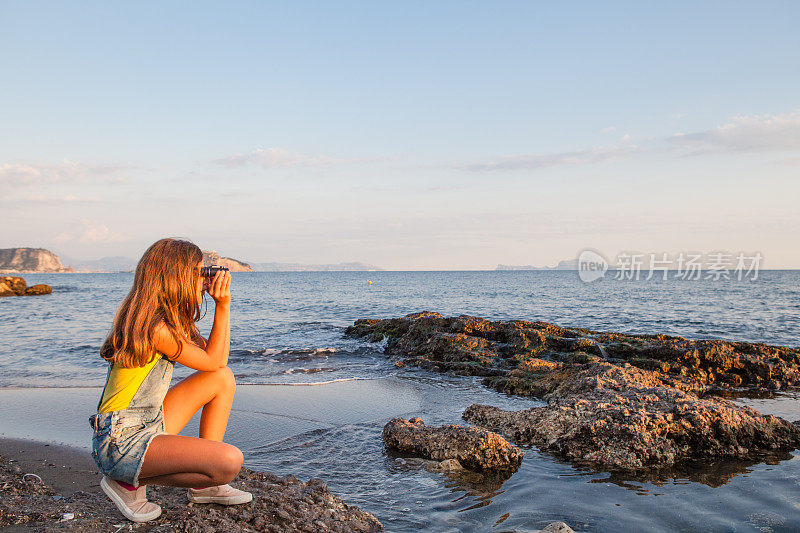 沙滩上的女孩用双筒望远镜看
