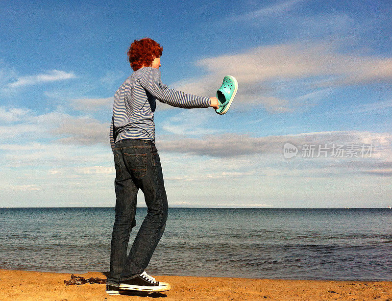 红发少年站在海滩上，面朝大海