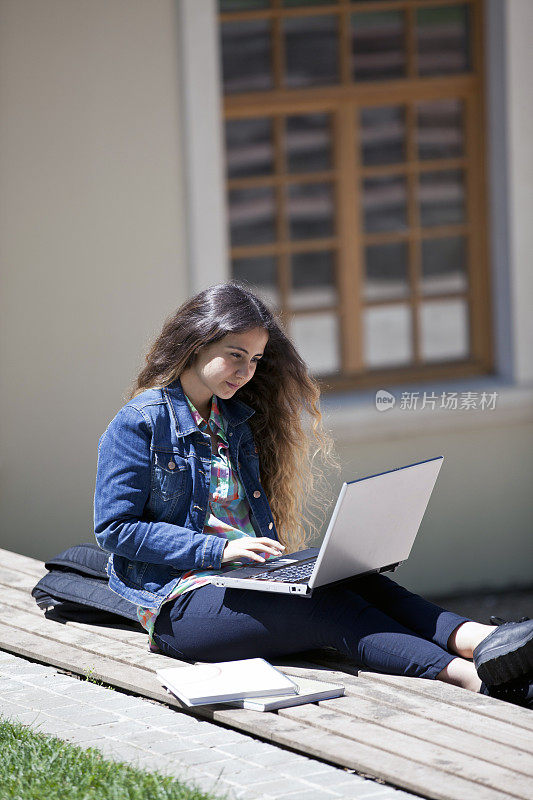 一个年轻女子在学校的花园里上网
