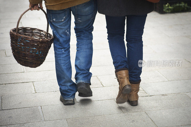 一对提着篮子在市场里散步的夫妇。