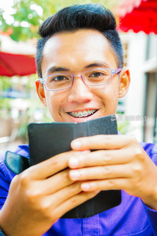 印度尼西亚男学生在他的电话微笑