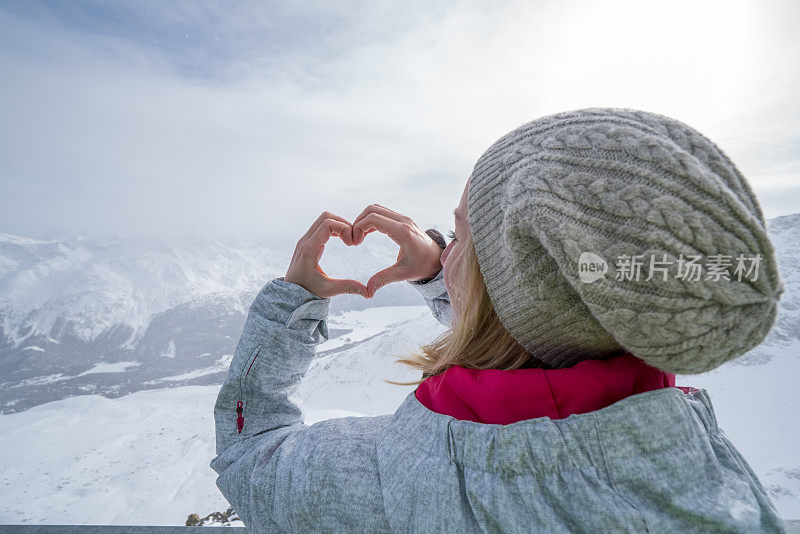 年轻女子在滑雪坡上做心形