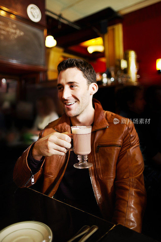 一个白人在餐厅里微笑着喝着热巧克力