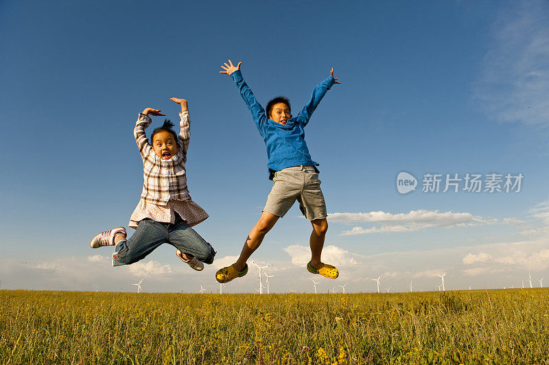 女孩和男孩在草地上跳跃