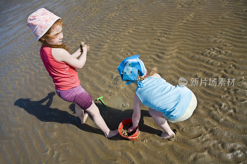 小女孩们赤脚在海边玩耍