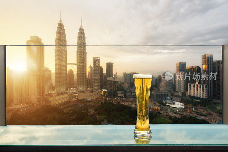 马来西亚吉隆坡，屋顶酒吧的桌上放着啤酒和泡沫啤酒，背景是吉隆坡摩天大楼。