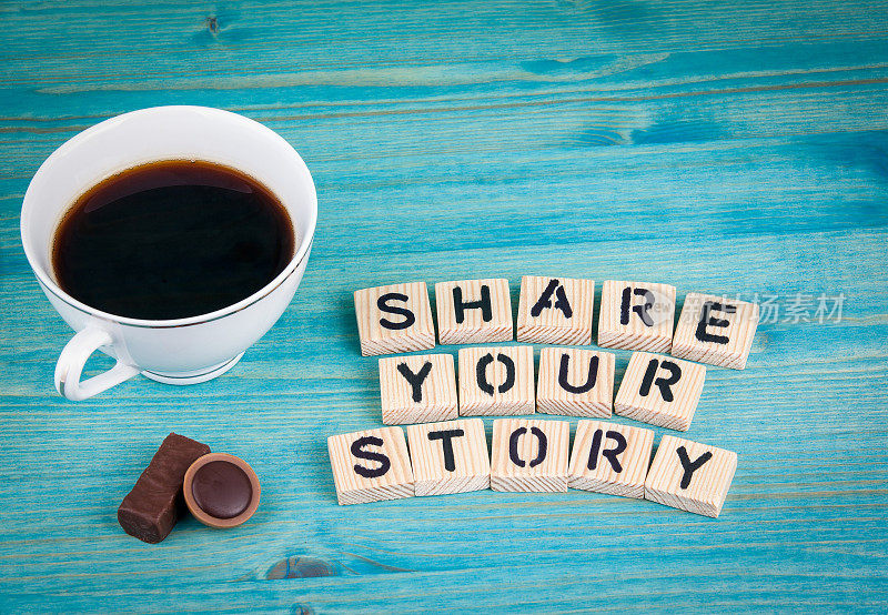 分享你的故事。咖啡杯和木头背景上的木头字母
