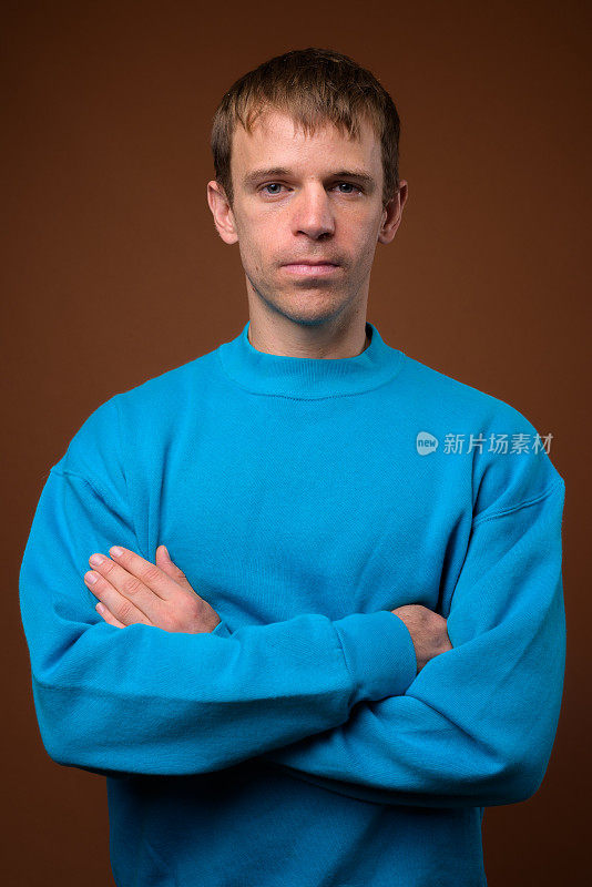 在彩色背景下，一名男子穿着蓝色毛衣