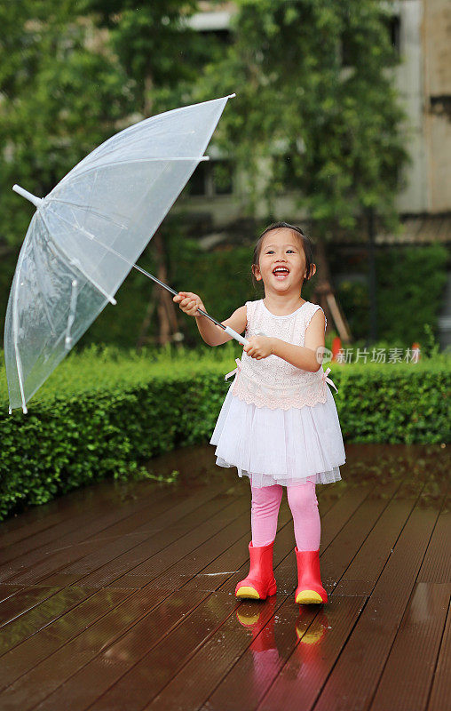 可爱的小女孩在雨中打着伞。