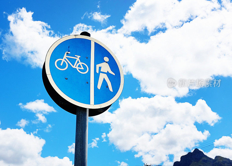 在一个指示行人和自行车道的标志后面的天空中的积云和层积云