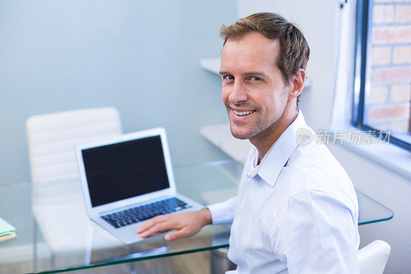 微笑牙医在笔记本电脑上工作的肖像