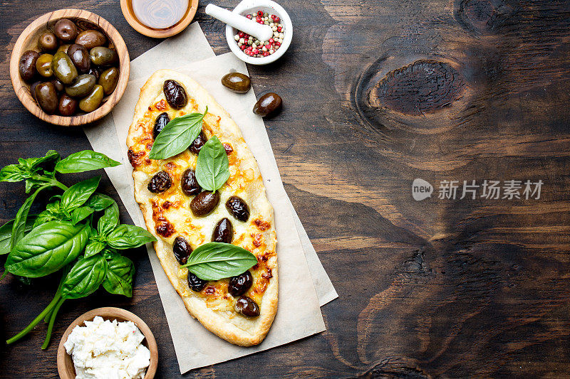 用橄榄和奶酪自制的椭圆形披萨。俯视图，复制空间