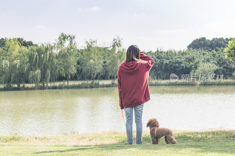 一个女人和她的小狗在湖边玩耍