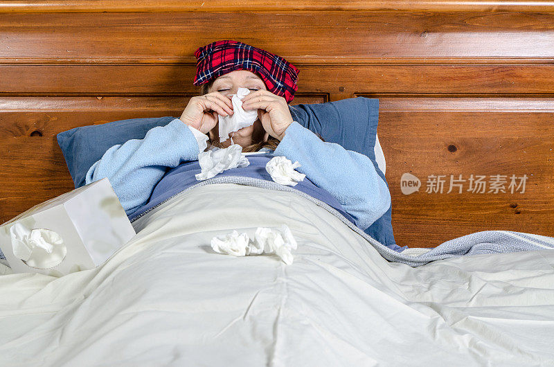 一个女人病在床上，用面巾纸擤鼻子