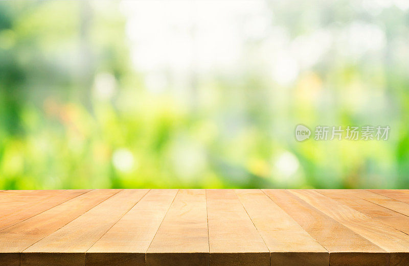 木制桌面模糊的绿色花园在早上的背景。