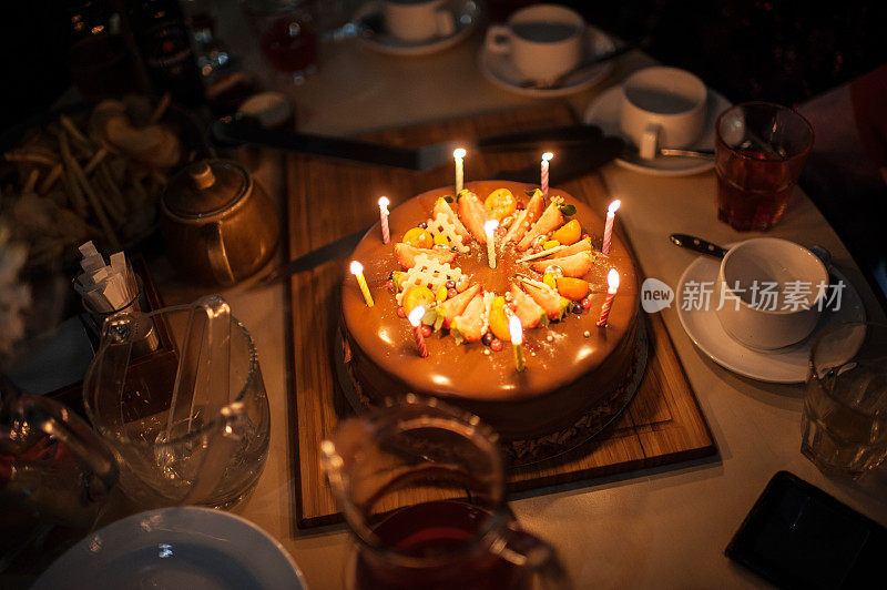 桌上放着点着蜡烛的节日蛋糕。生日快乐。