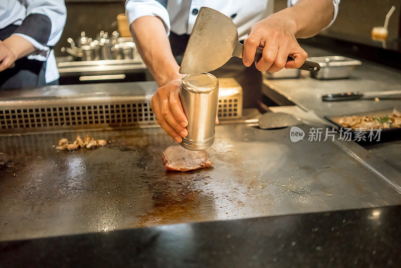 厨师在顾客面前将胡椒放入热锅中。日本Tepanyaki牛排