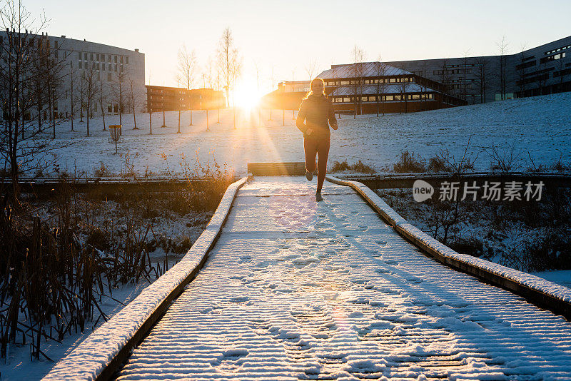 年轻女运动员在阳光明媚的冬日跑步。