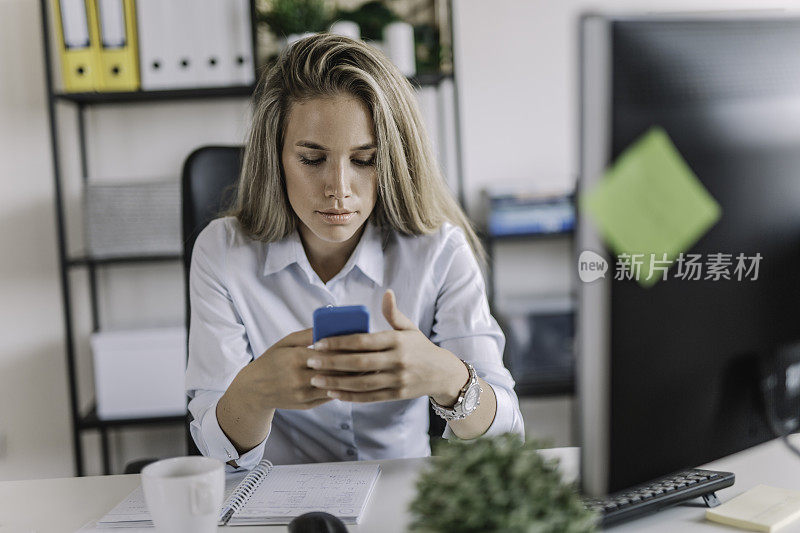 年轻女商人在办公室使用智能手机