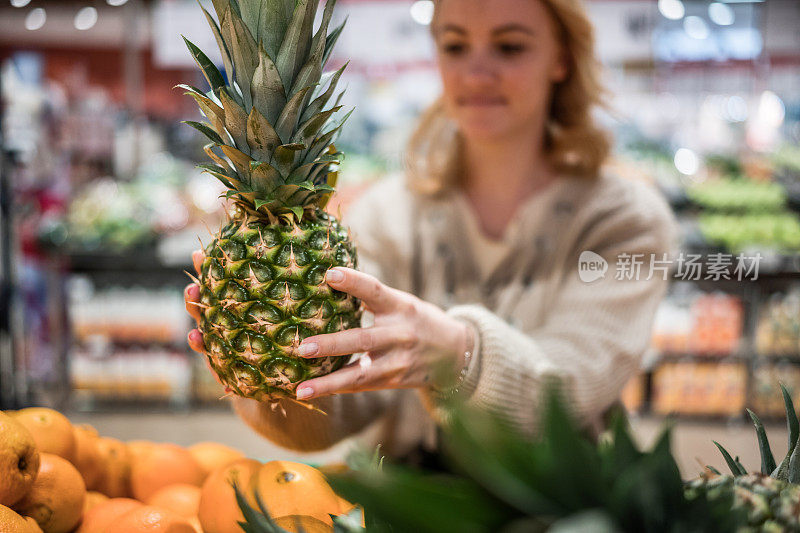 女人在杂货店买菠萝的特写。