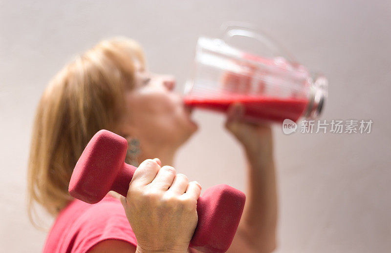 健康的生活方式:女人举重，喝冰沙