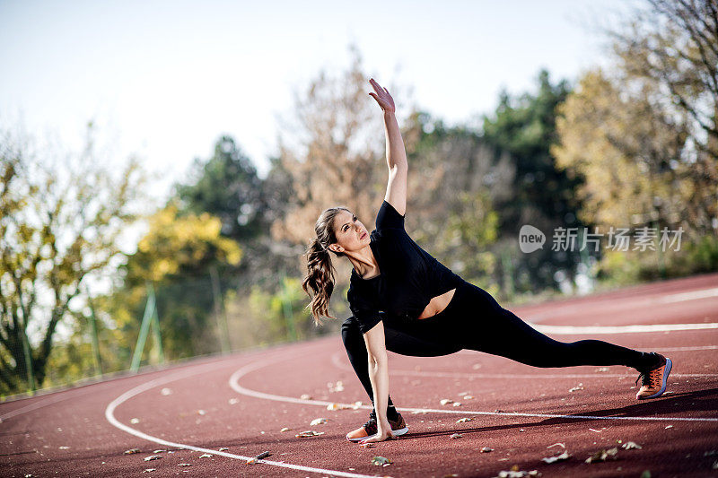 美丽的运动运动女人伸展在运动轨道上