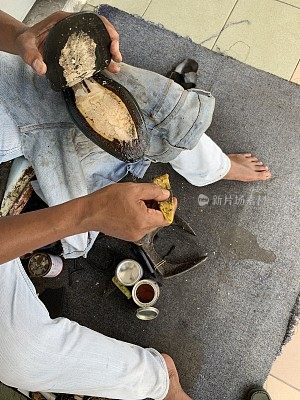 街道上，一个男修鞋匠正在他的作坊里修理一只皮鞋