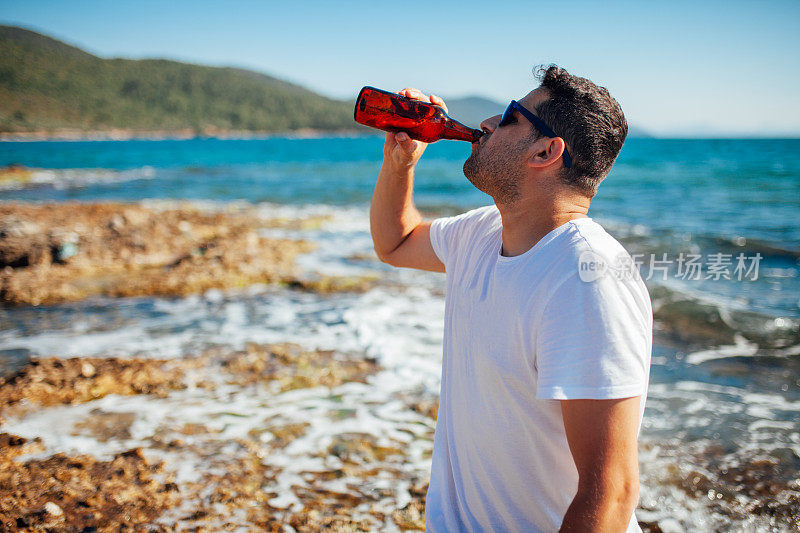 在海滩上喝啤酒的男人